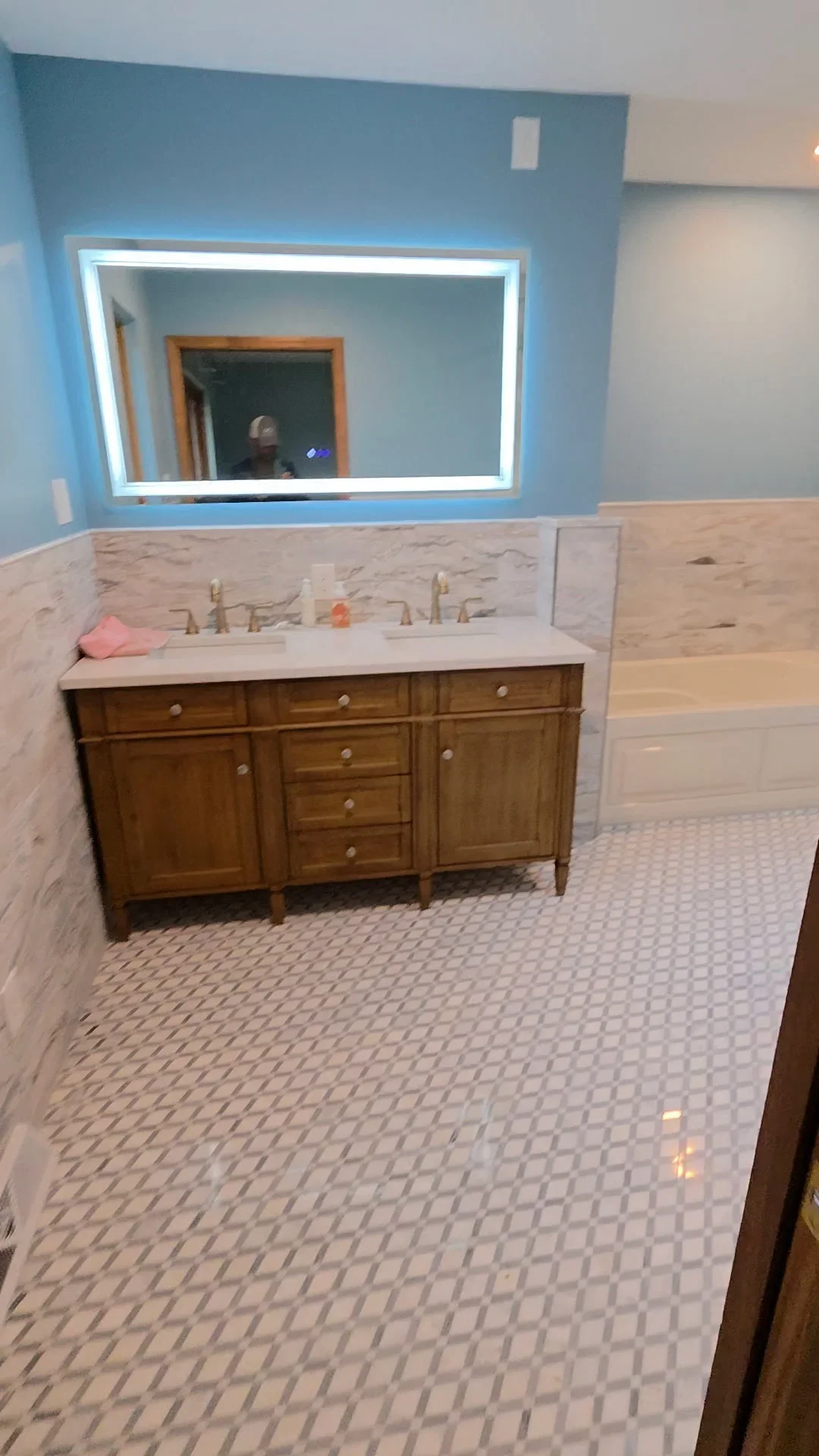 Master bathroom with marble wainscot, dual vanity, LED mirror, and hexagonal floor tile
