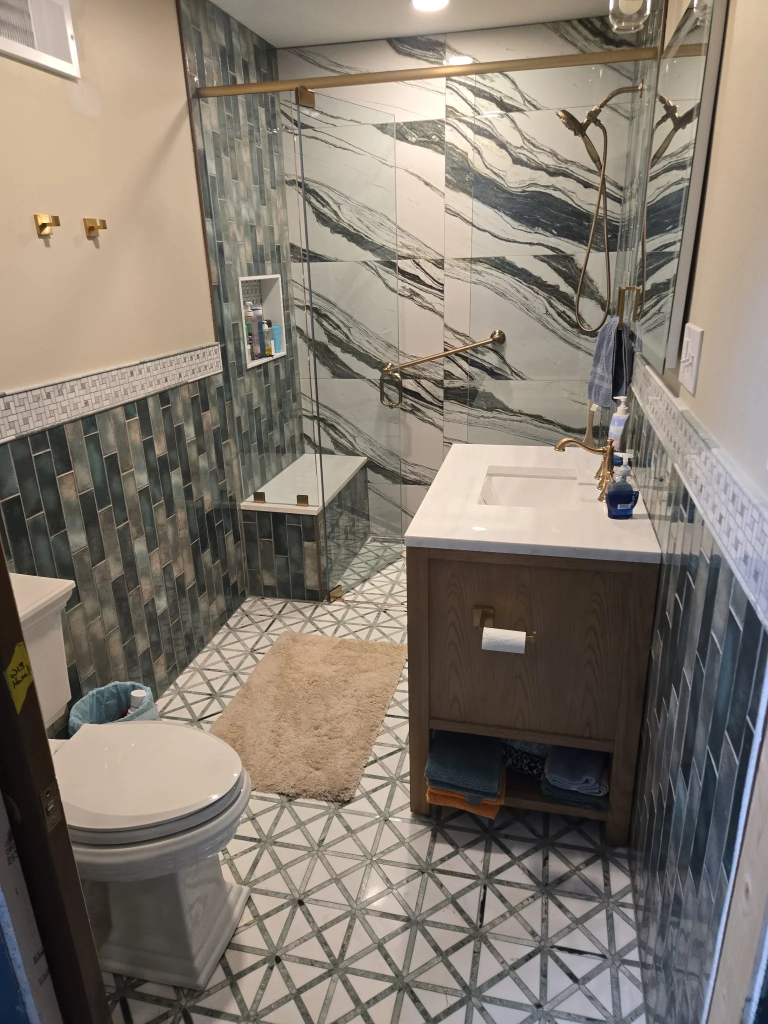 Renovated bathroom with marble tile shower, custom vanity, and geometric floor pattern