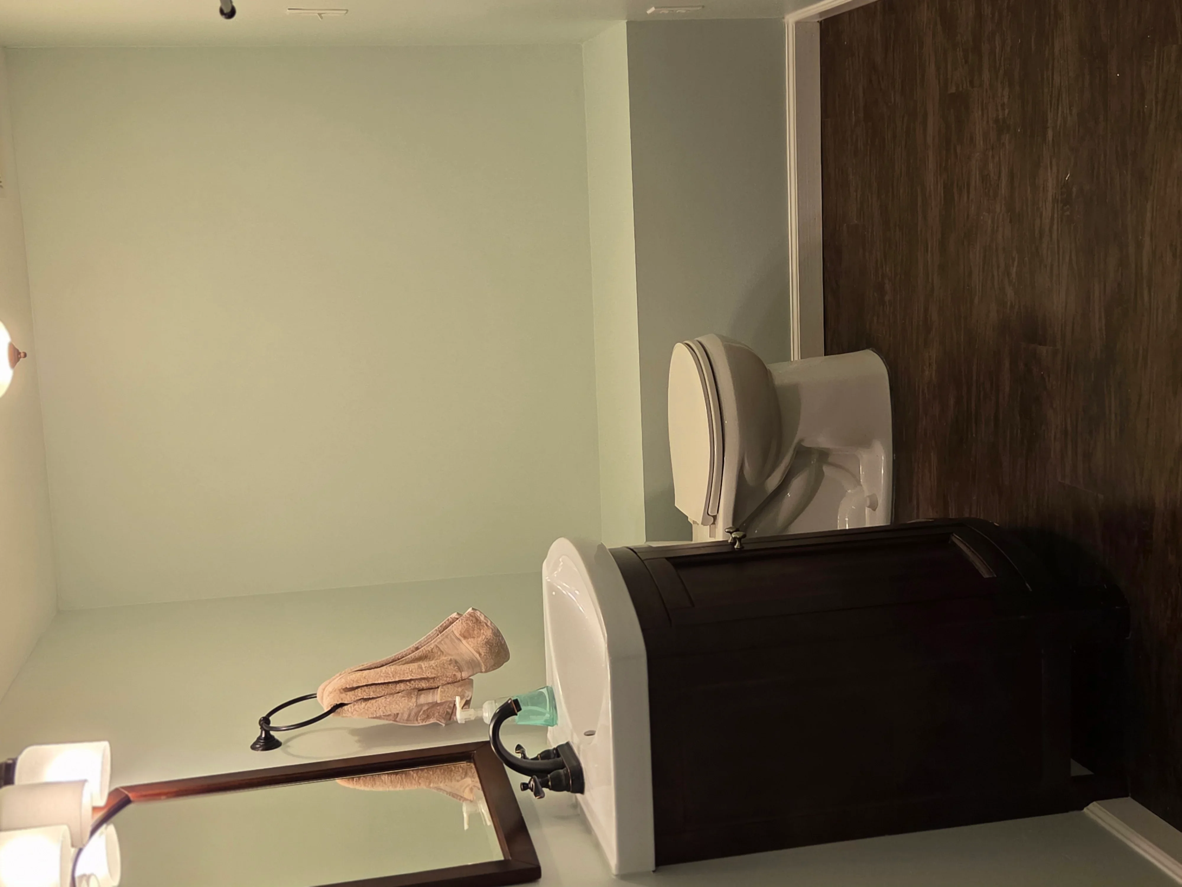 Bathroom vanity with dark wood cabinetry, white countertop, and chrome fixtures