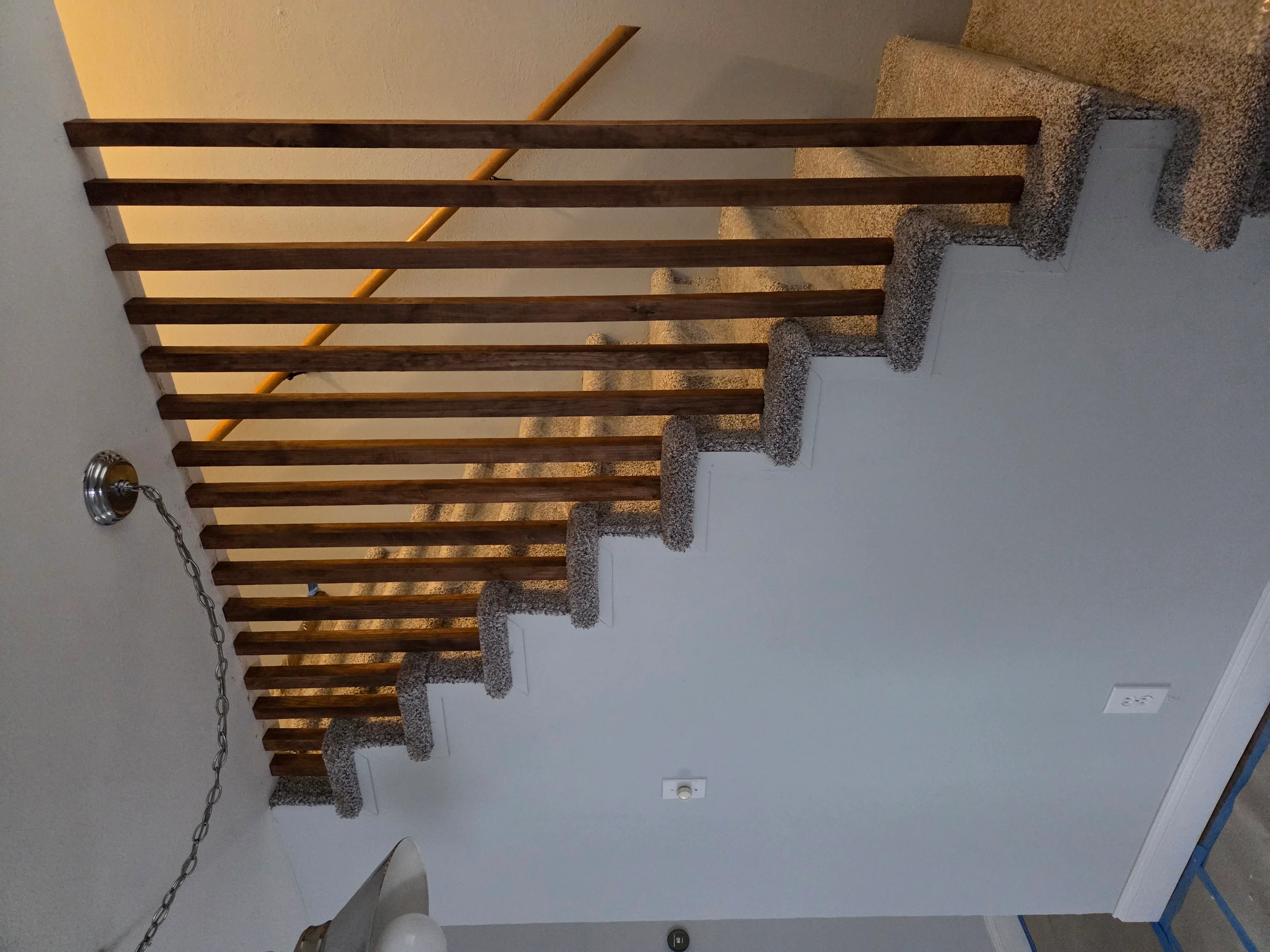 Dark wood exposed beams installed in geometric pattern on drywall ceiling with recessed lighting