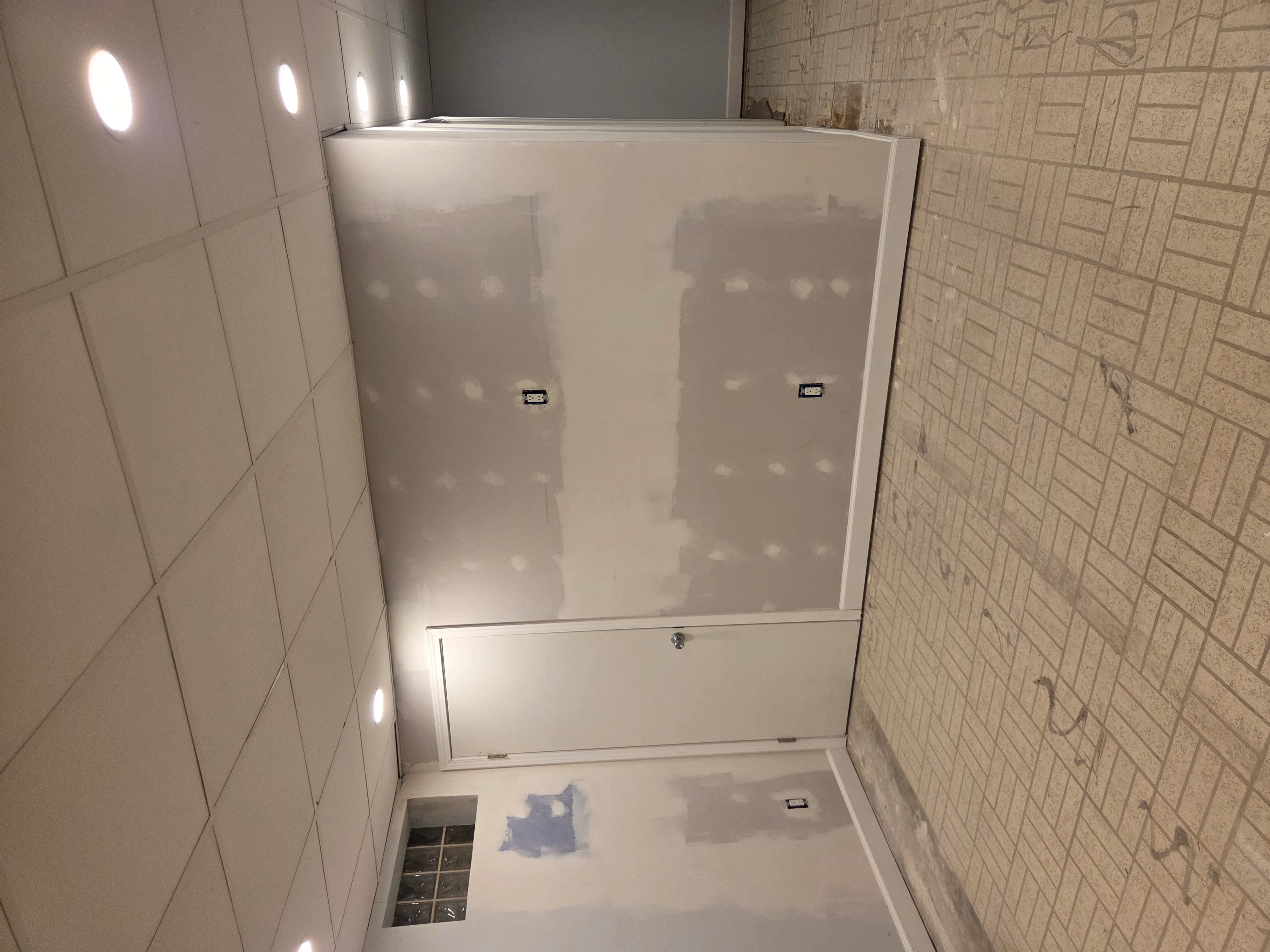 Frameless glass shower enclosure with sliding doors, white subway tile walls, recessed lighting