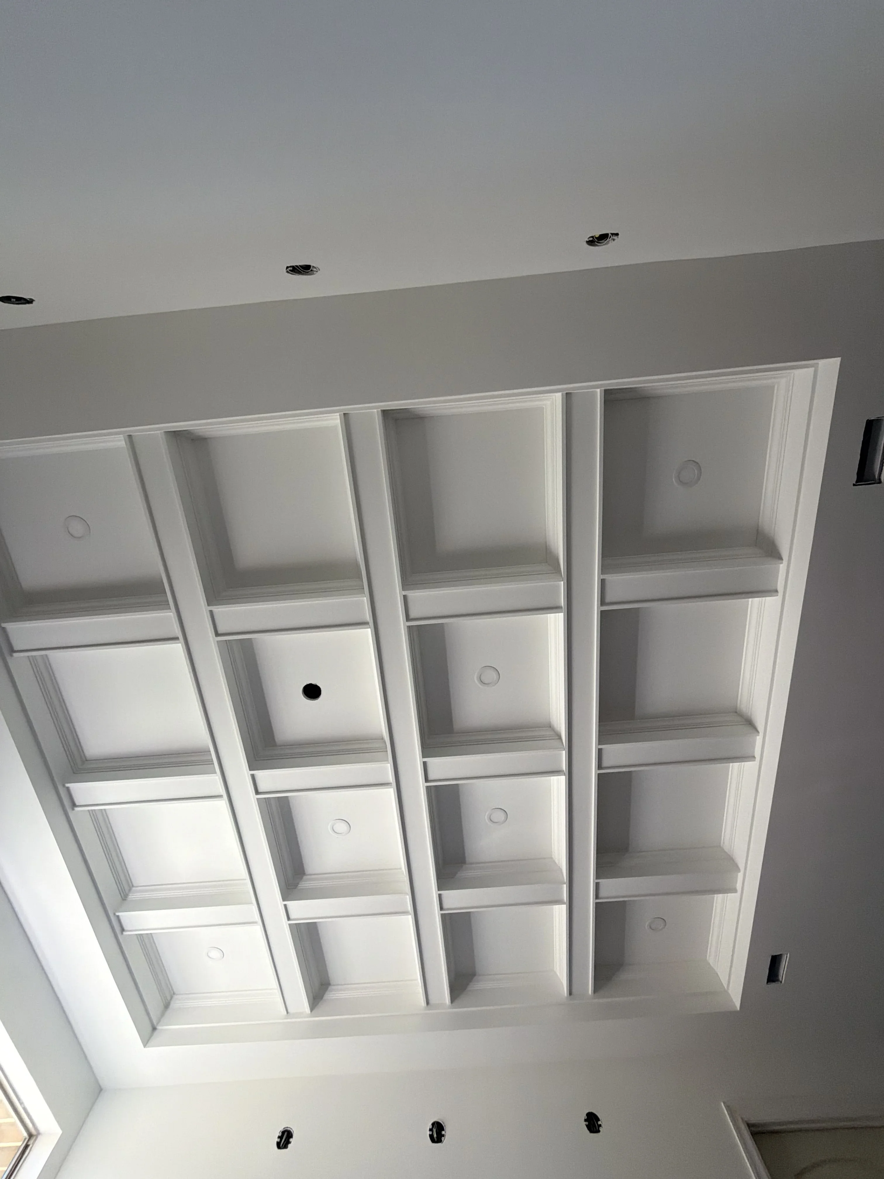White coffered ceiling with recessed lighting and geometric beam pattern